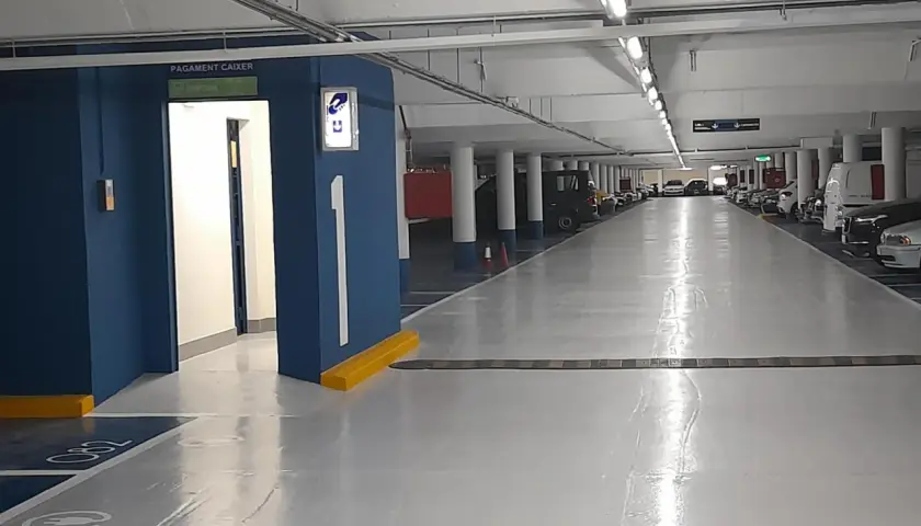 Entrada al parking Rius i Taulet. Pasillo con coches aparcados y señalización de salida.