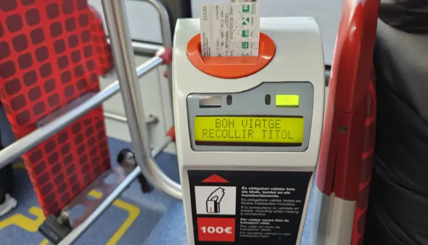 Validando billete para prendre le bus a Barcelone. Asientos rojos con patrón de cuadros en el interior del autobús.