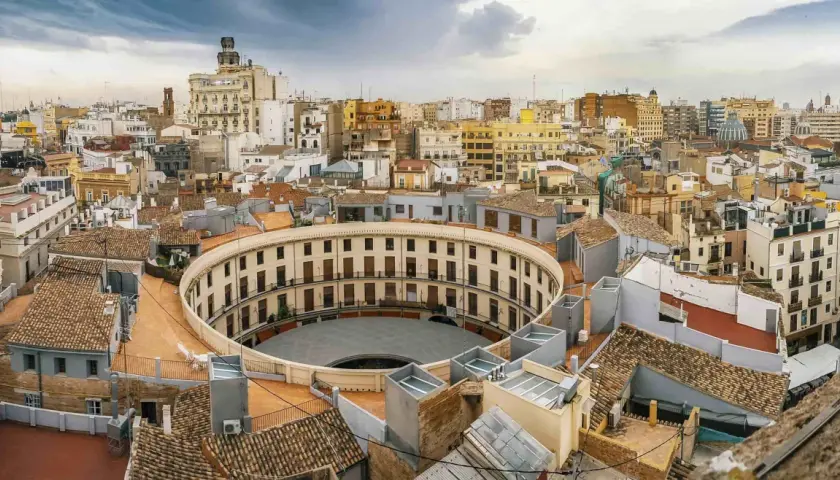 Vista aérea de la Plaza de Toros de Valencia, un edificio circular con balcones, como si se viajara en el tren de Barcelona a Valencia.