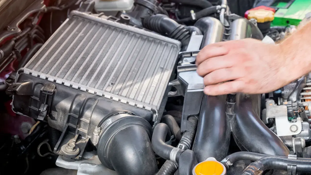 Mano ajustando un intercooler, componente clave para enfriar el aire del motor.