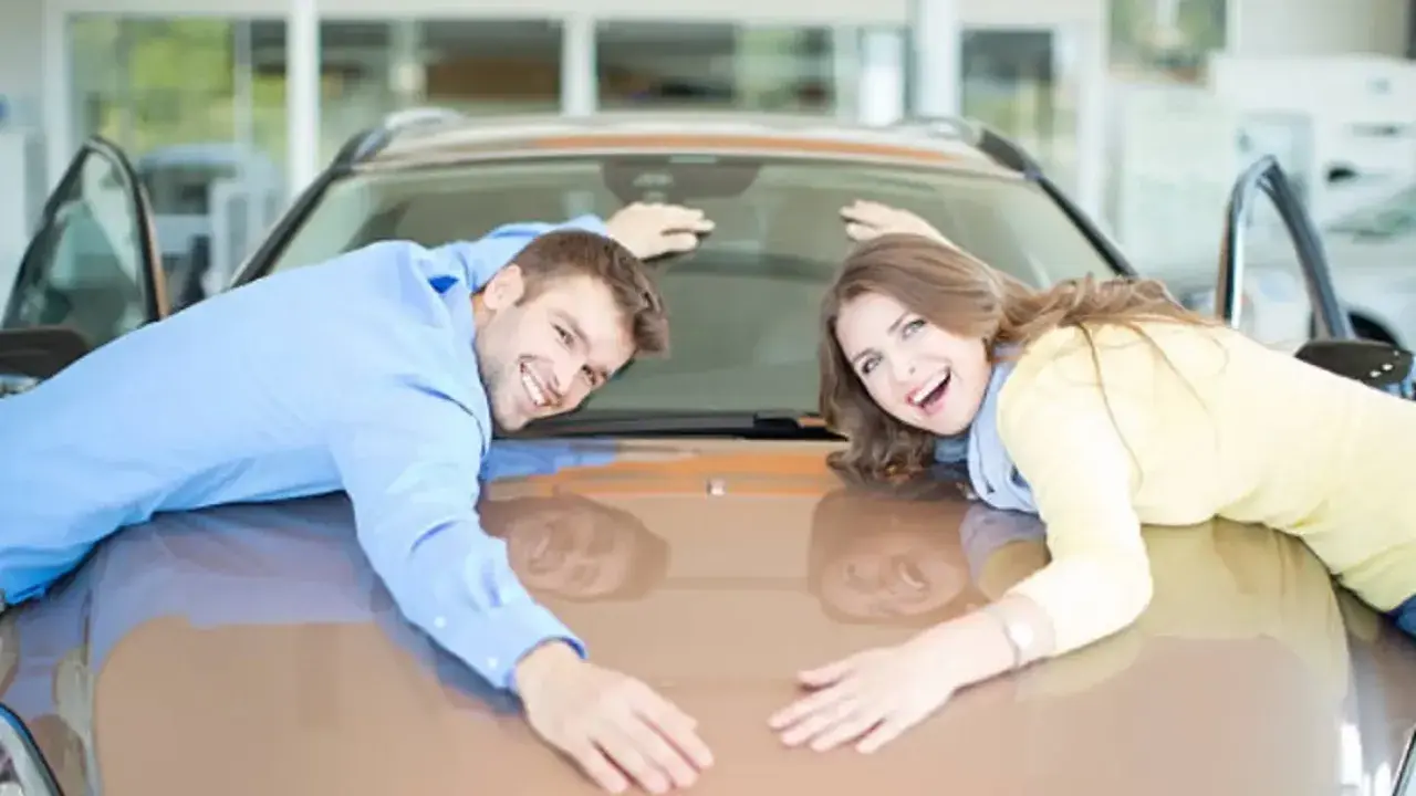 Pareja feliz abraza su nuevo coche, demostrando que se puede poner un coche a nombre de dos personas.