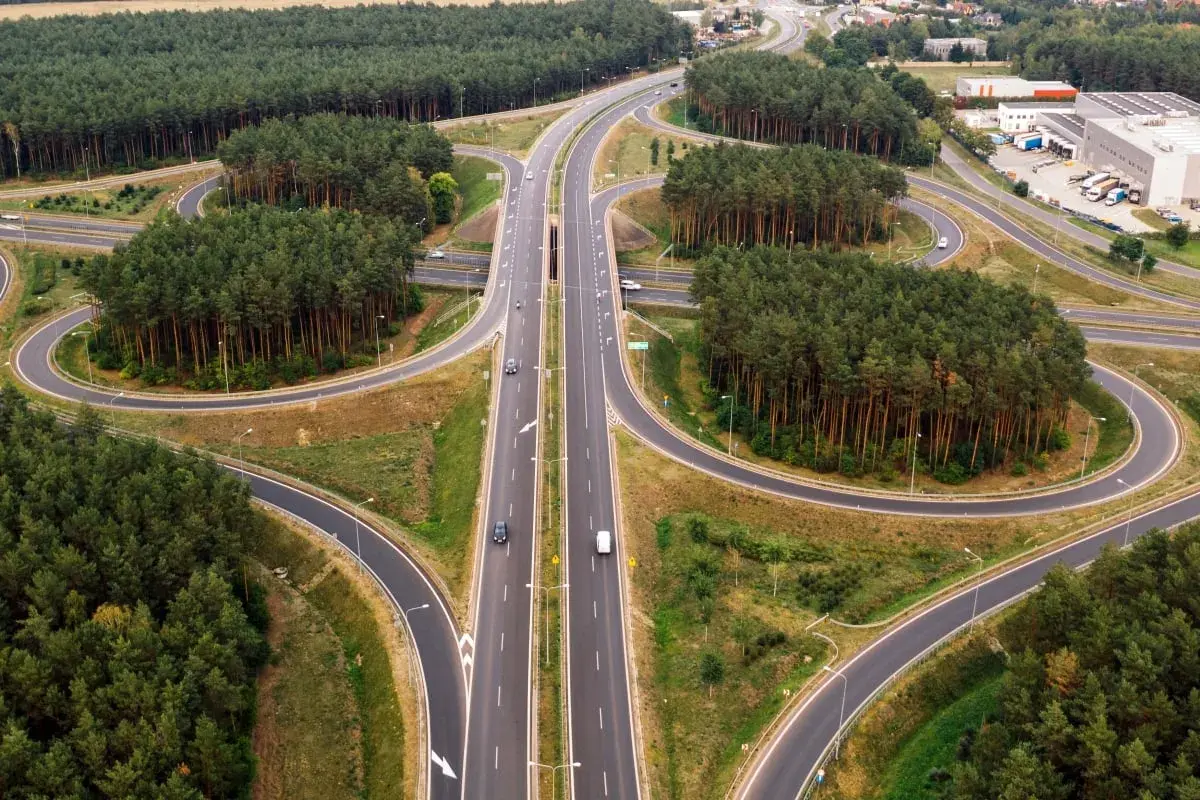 Un cruce de autopistas con un carril trenzado serpentea entre bosques de pinos.