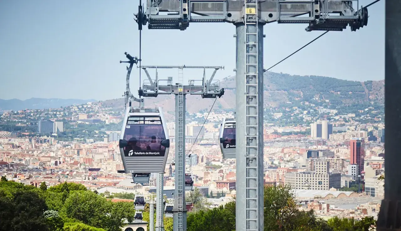 El teleférico de Montjuïc ofrece vistas panorámicas de Barcelona. Varias cabinas se deslizan sobre la ciudad, conectando puntos clave.