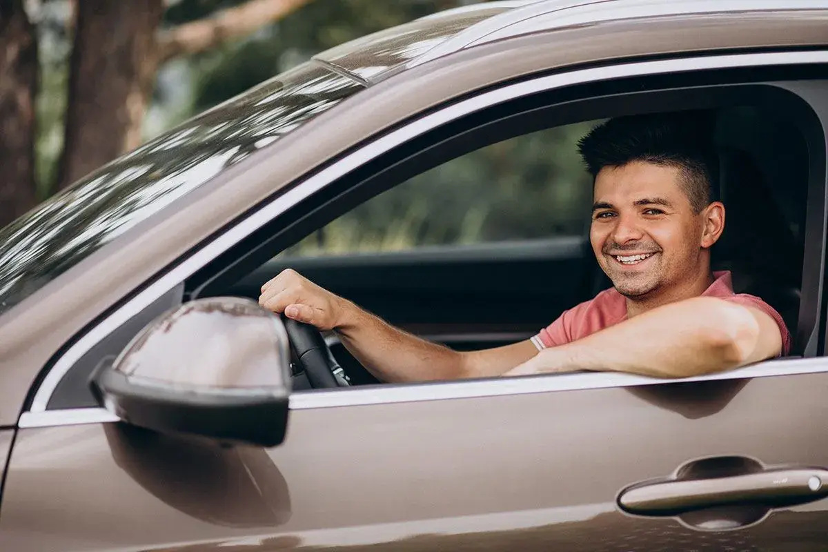 Hombre sonriente al volante, disfrutando de un viaje. La pregunta sobre hasta qué edad se puede conducir en España es relevante para muchos.