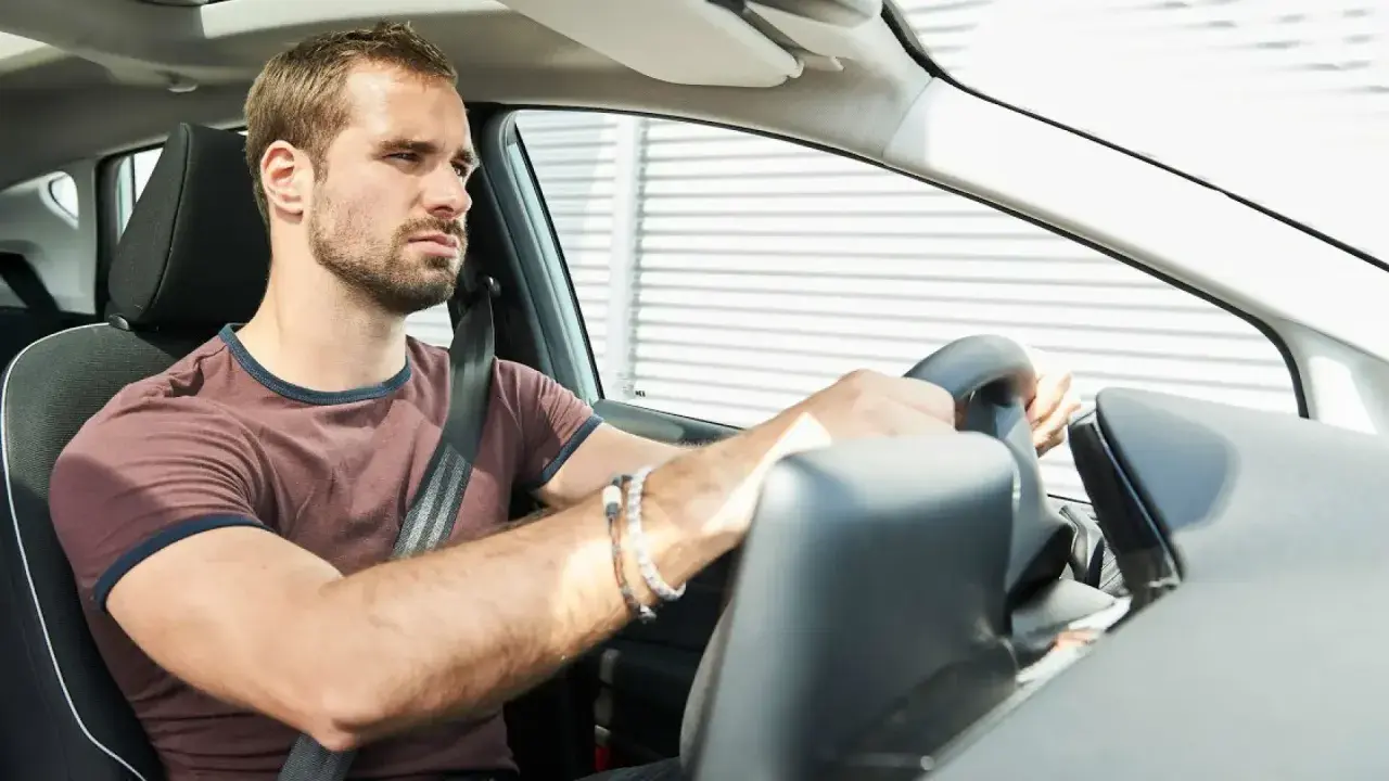 Hombre frustrado al volante, su coche no arranca.