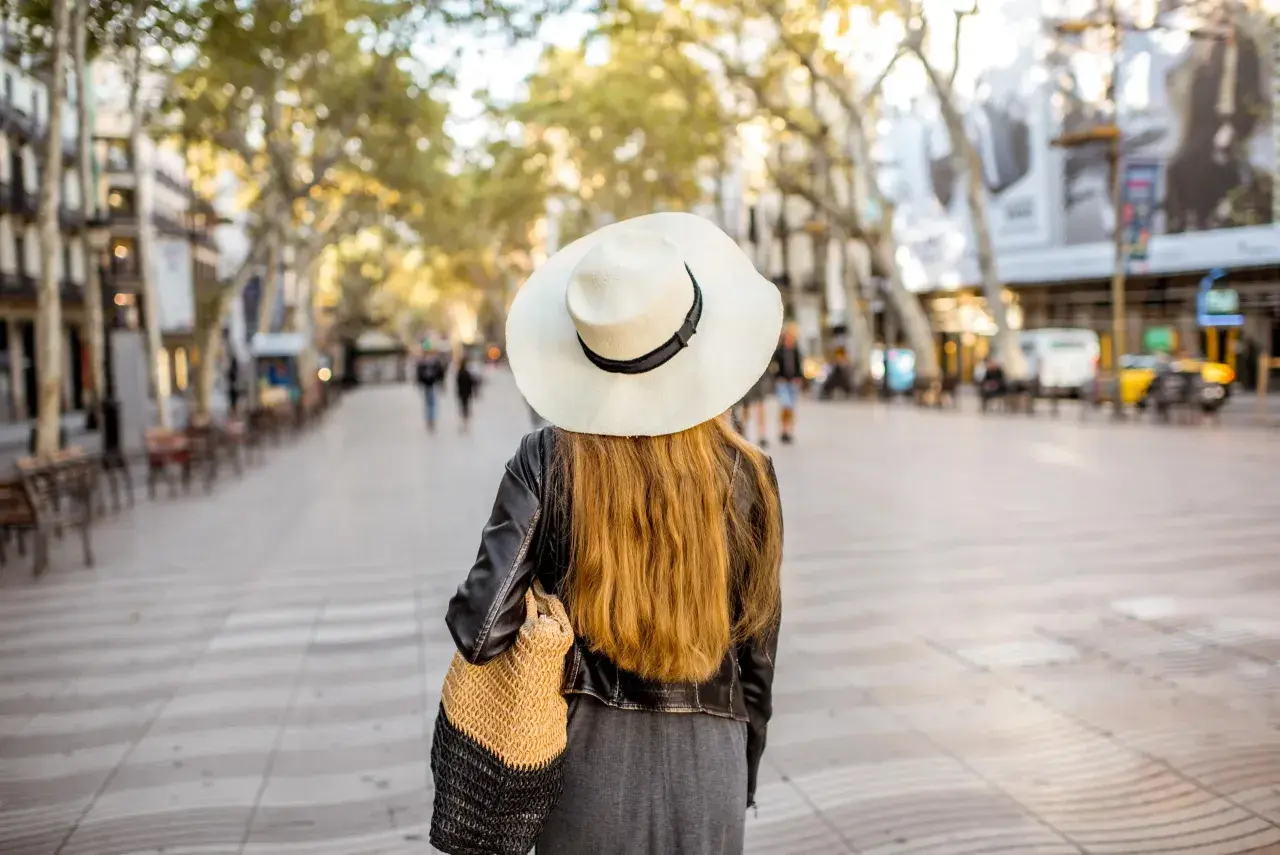 Mujer con sombrero pasea por Las Ramblas de Barcelona, un mapa visual de la ciudad.