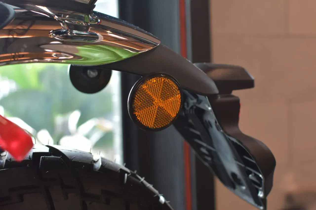 Detalle de una moto con un catadióptrico naranja que refleja la luz, aumentando la seguridad.