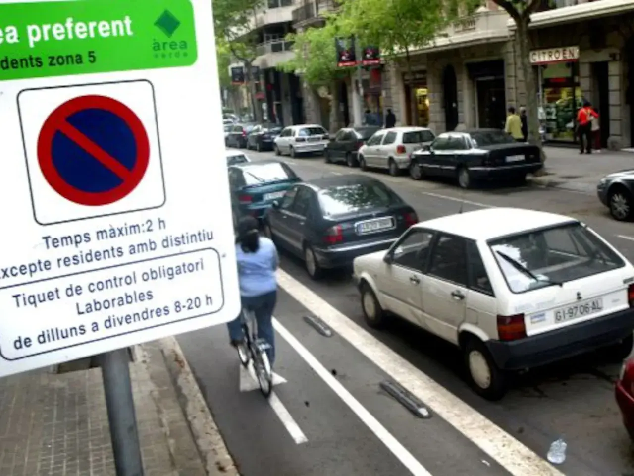 Zona verte Barcelona domingo: señal de estacionamiento, ciclista y coches aparcados en la calle.