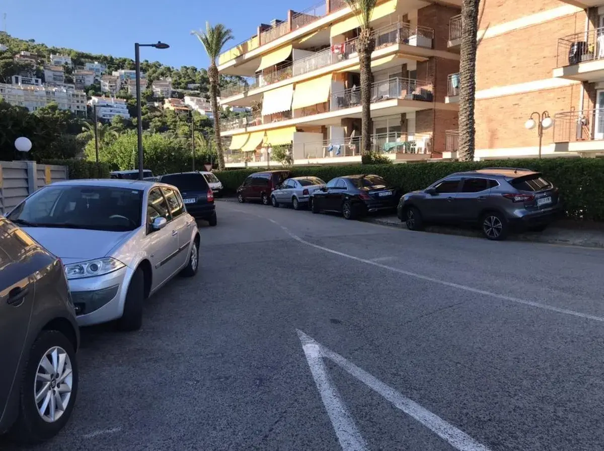 Coches aparcados en una calle con edificios residenciales al fondo. Hay varias opciones de parking gratuit Sitges.