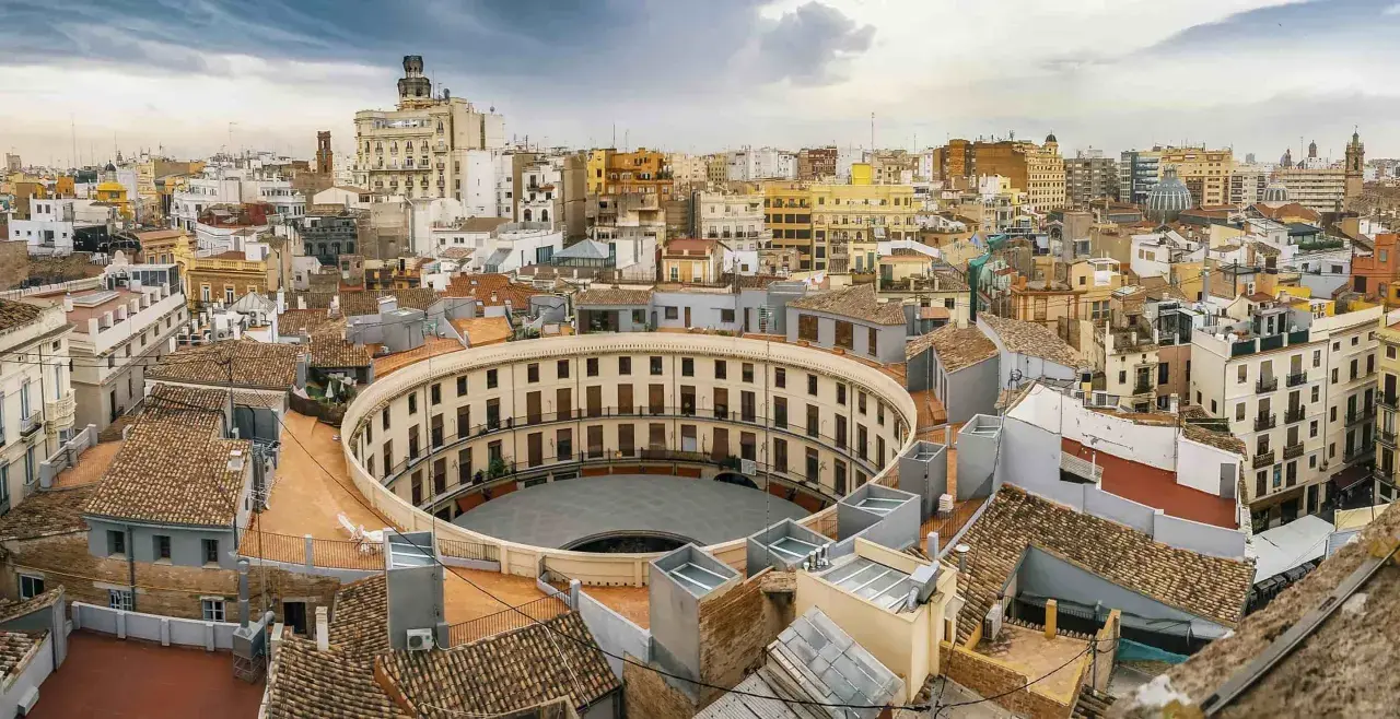 Vista aérea de la Plaza de Toros de Valencia, un edificio circular con balcones, como si se viajara en el tren de Barcelona a Valencia.