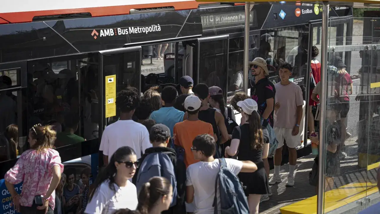 Turistas esperan el transporte en Barcelona. Un autobús AMB Bus Metropolità está listo para llevarlos a su destino.