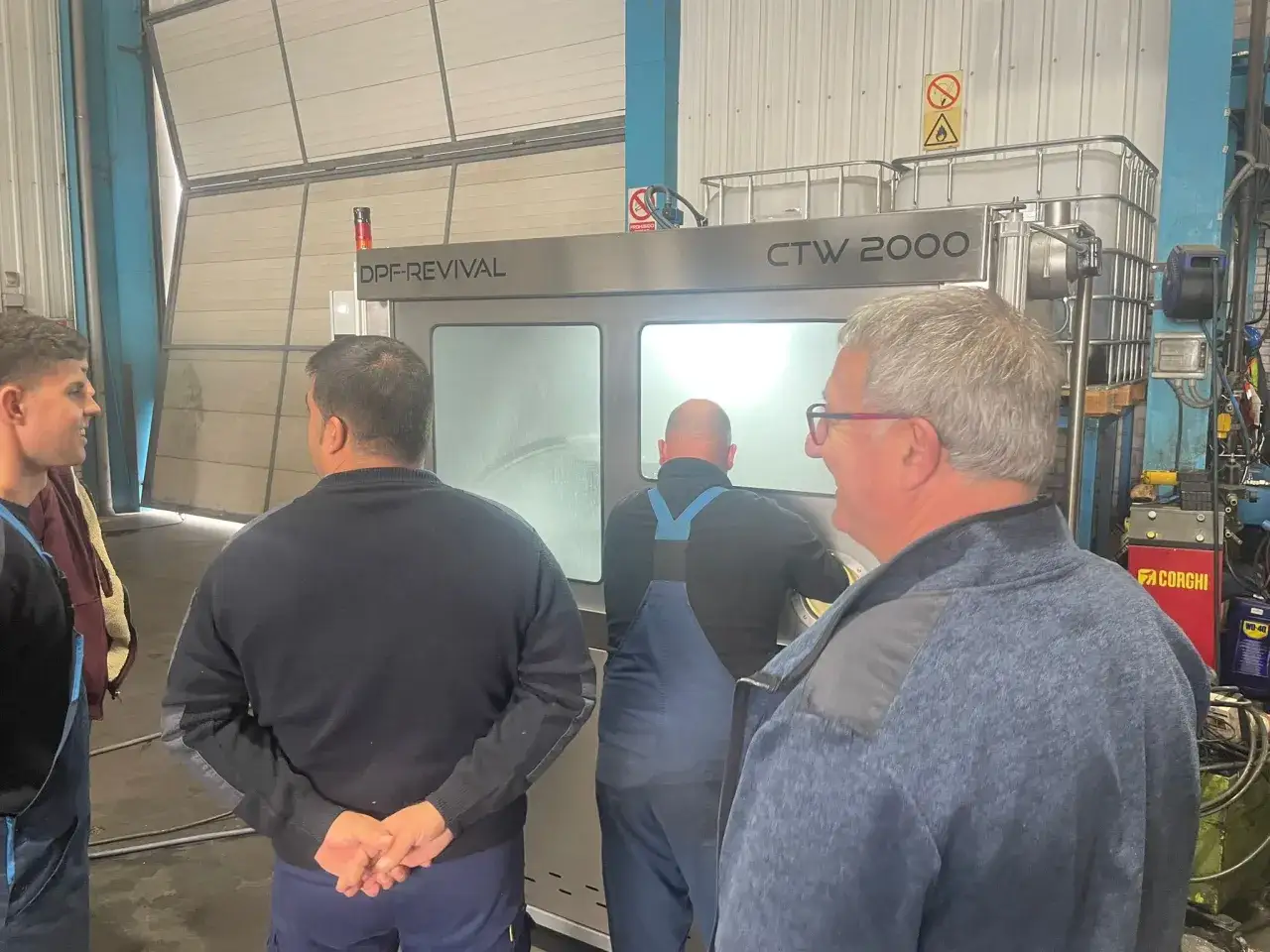 Hombres observan máquina DPF-REVIVAL CTW 2000, aprendiendo como limpiar el filtro de particulas.