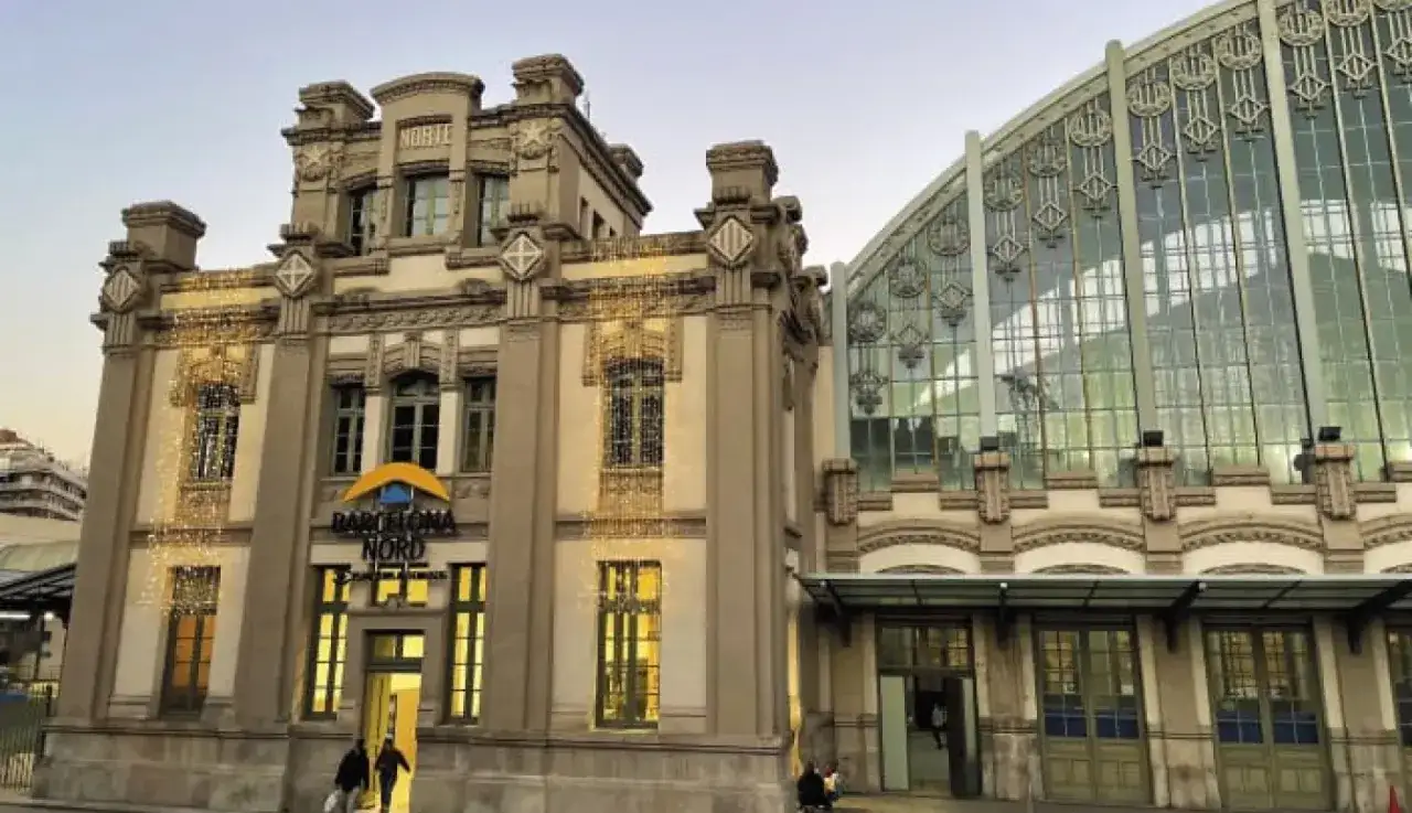 Edificio histórico de la estación de autobuses Barcelona Nord, con su fachada ornamentada y una moderna estructura de cristal.