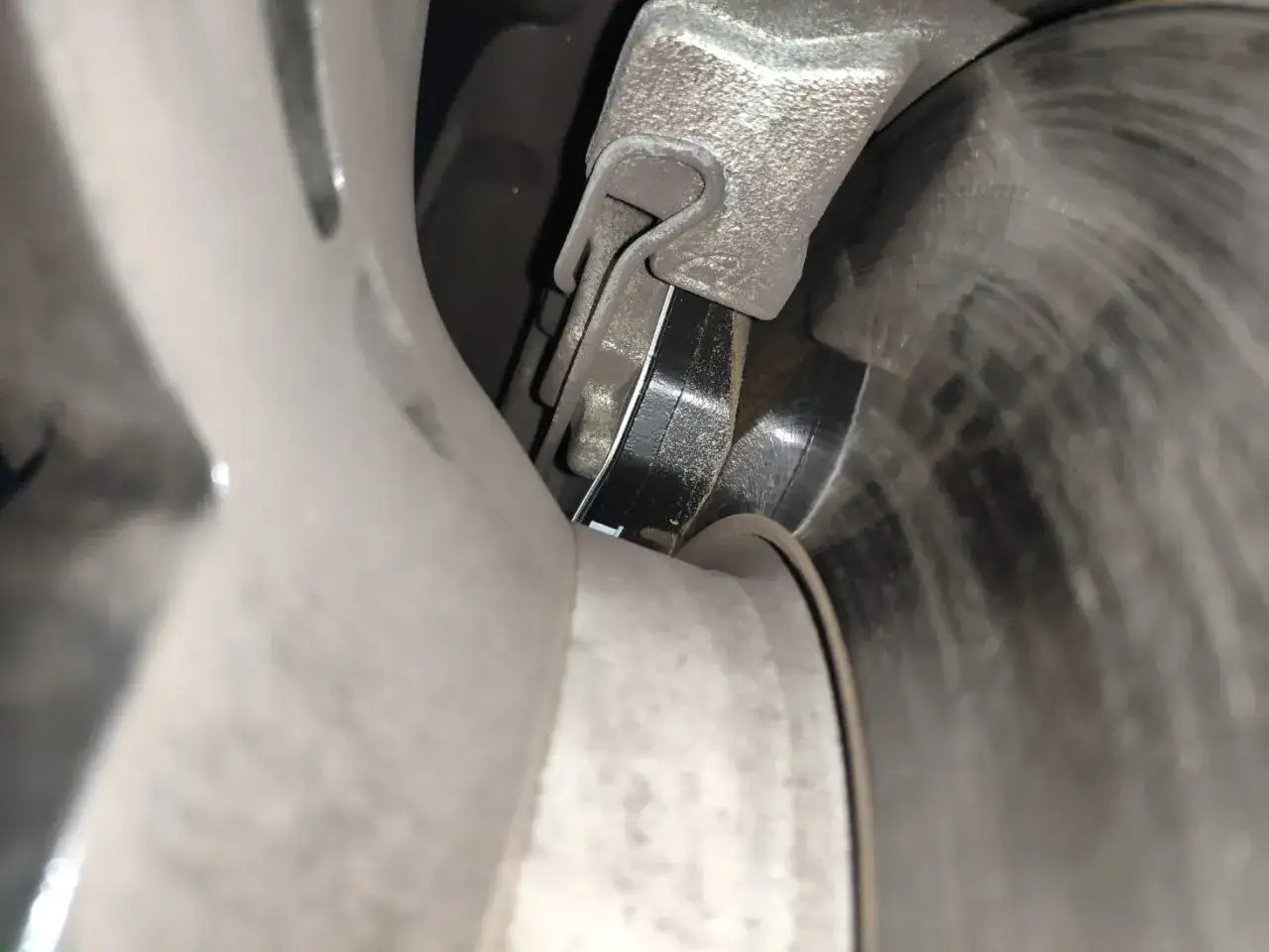 Primer plano de pastillas de freno gastadas, mostrando el desgaste del material de fricción contra el disco.