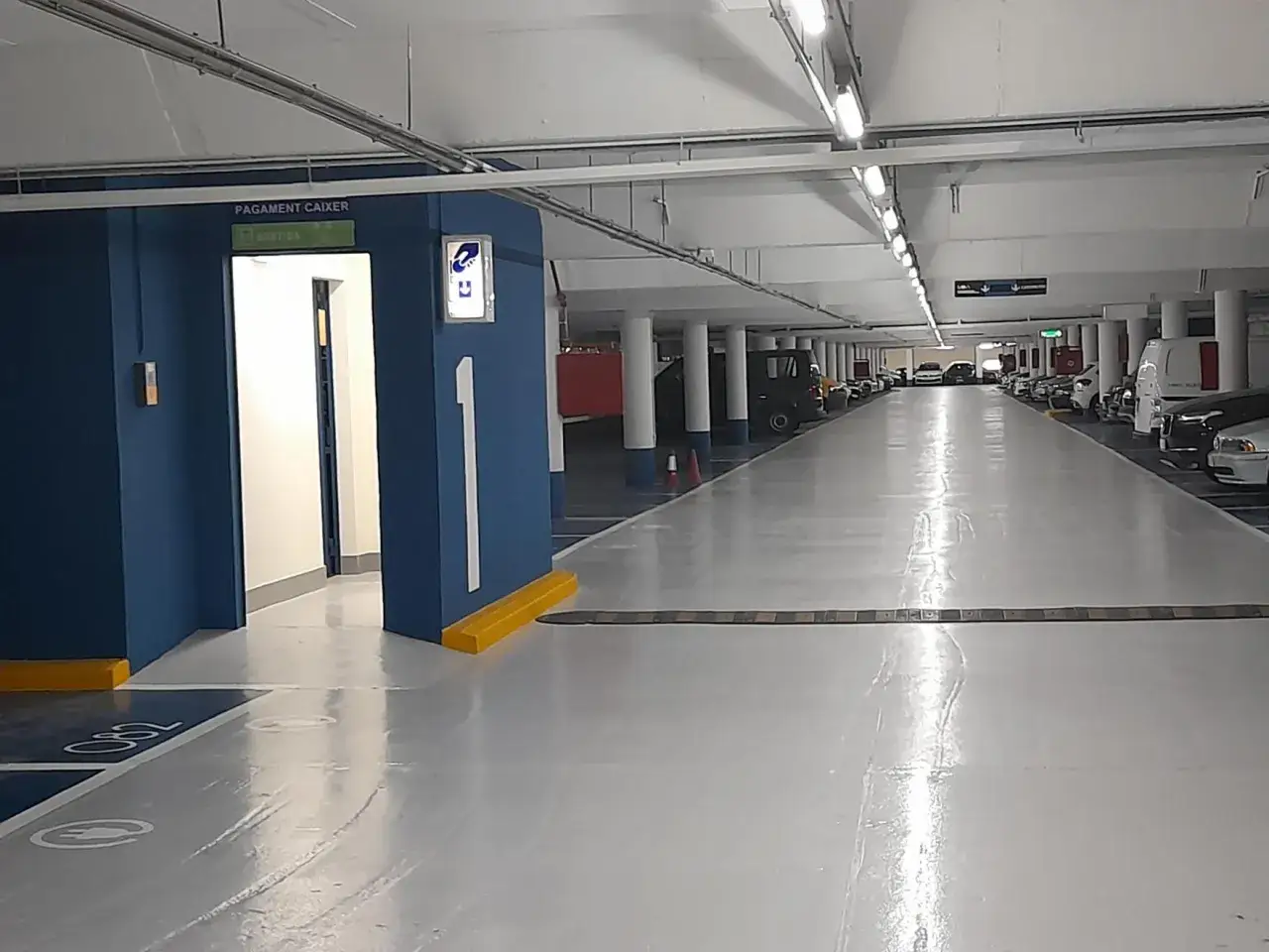 Interior de un parking subterráneo con coches aparcados. Señal de