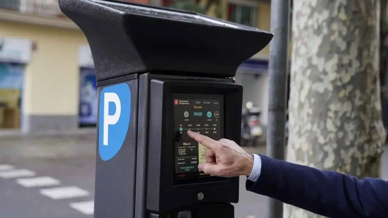 Un hombre interactúa con un parquímetro. Los coches con etiqueta 0 pagan zona azul, pero este parquímetro muestra tarifas y duración.