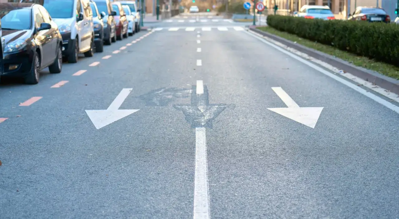 Flechas en el asfalto indican cu&aacute;ndo se puede adelantar por la derecha. Coches aparcados a la izquierda.