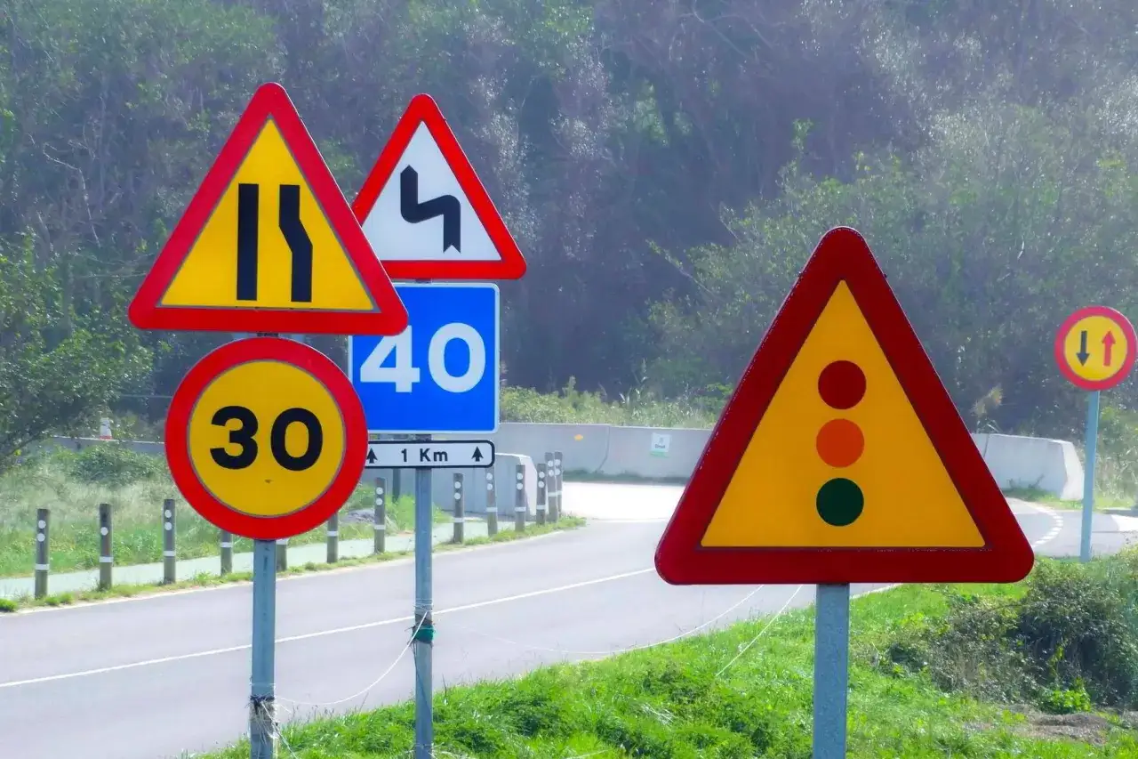 Señales de tráfico advierten de estrechamiento de vía, curvas peligrosas, límite de 30 y 40 km/h, y un semáforo. La prioridad de paso es clave.