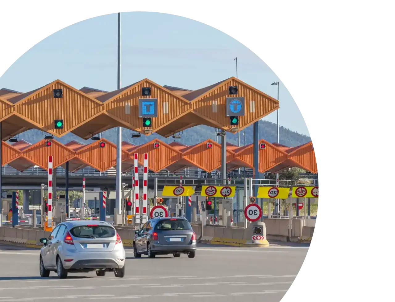 Coches circulando por una estación de peajes en Cataluña. Las barreras están bajadas y los semáforos en rojo.