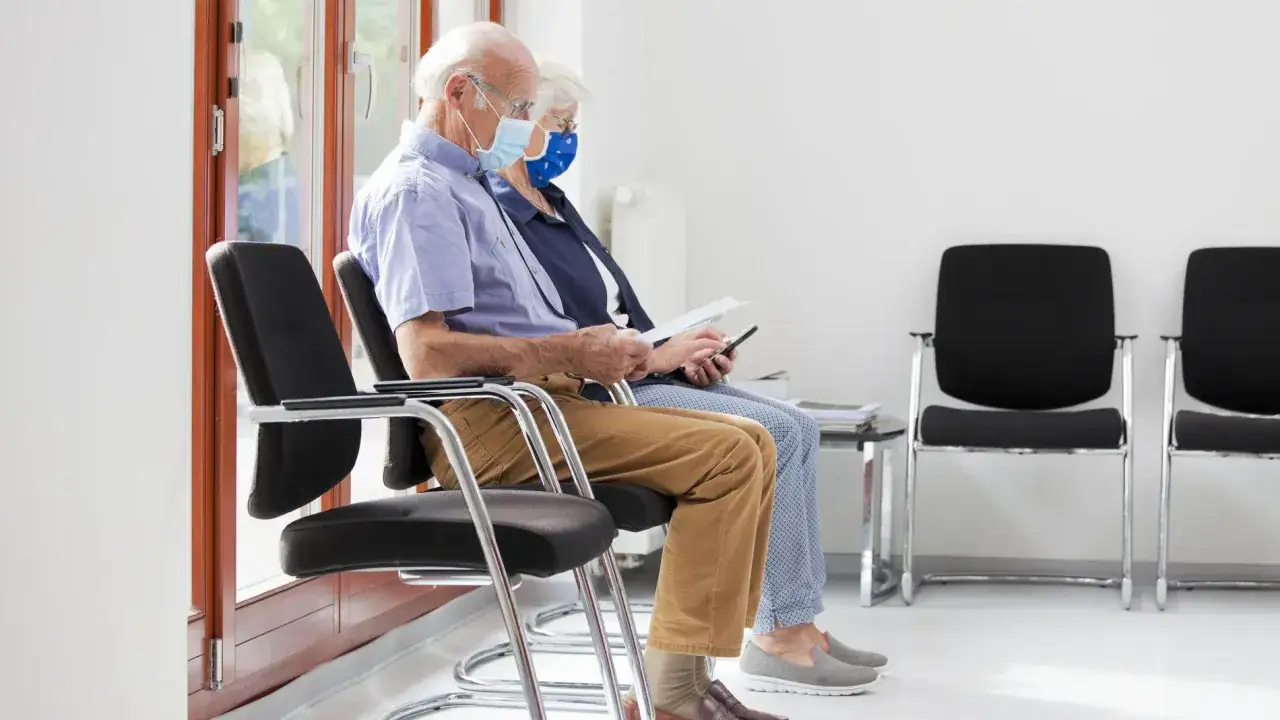 Pareja mayor con mascarillas esperando. Se preguntan hasta qu&eacute; edad se puede conducir en Espa&ntilde;a.